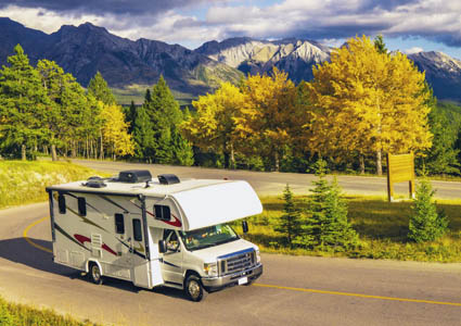 Rv driving on the road with mountains and trees in the background